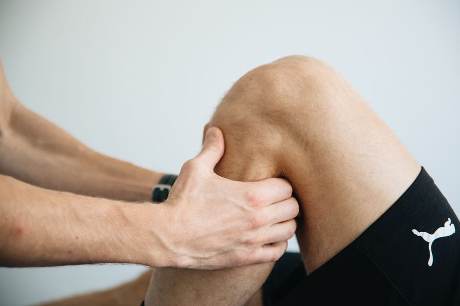 Physiotherapeutin behandelt das Knie einer Patientin