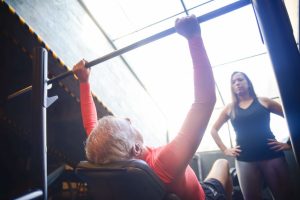 Aeltere Person beim Krafttraining mit Trainer