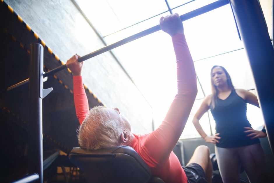 Aeltere Person beim Krafttraining mit Trainer