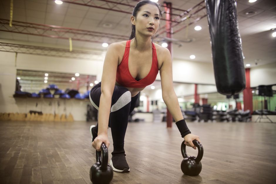 Frau fuehrt eine Kniebeuge mit Kettlebell im Training durch