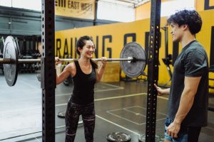 Ein Paar trainiert gemeinsam mit Hanteln im Fitnessraum