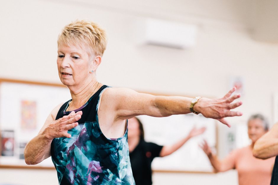 Seniorin trainiert Balance und Kraft in einer Fitnessgruppe