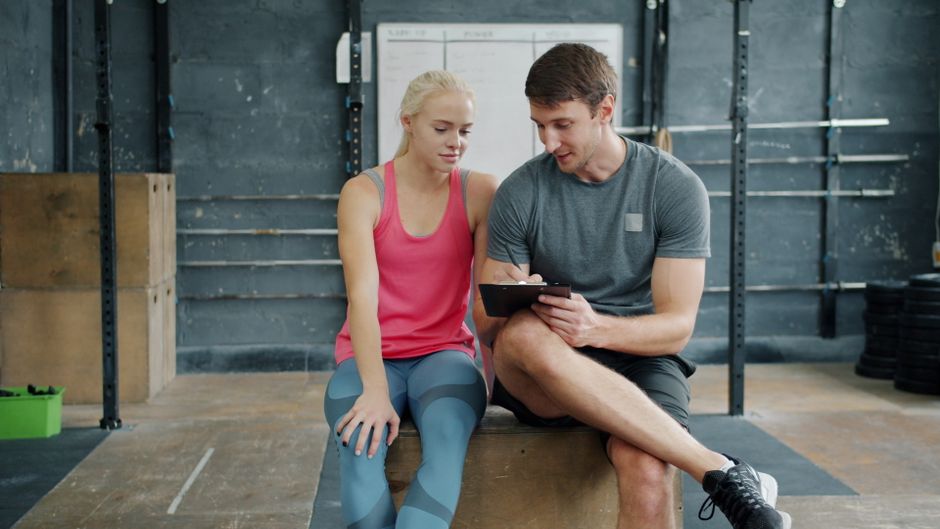 Personal Trainer bespricht mit einer Kundin den Trainingsplan